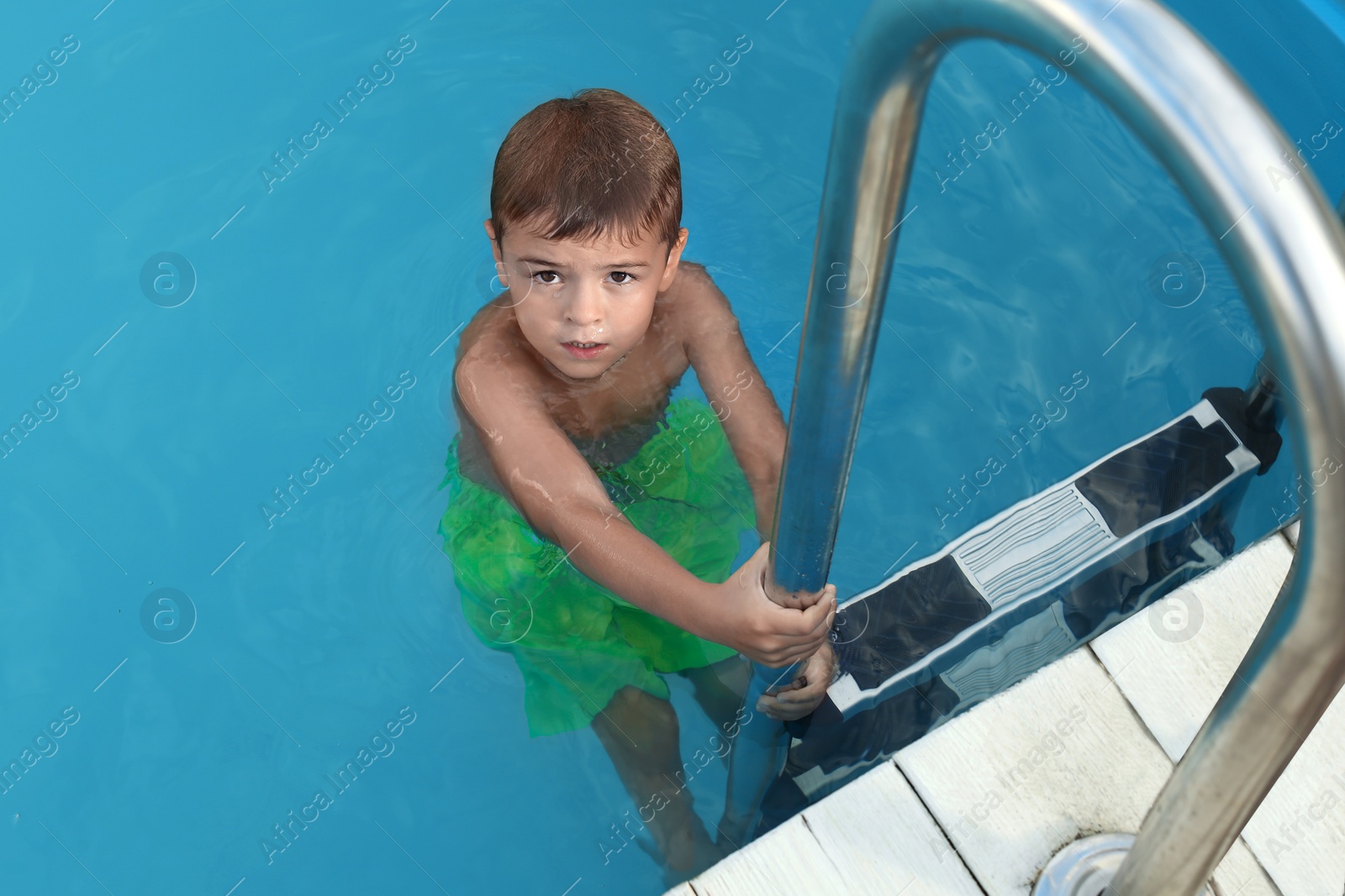 Photo of Little child getting out of outdoor swimming pool. Dangerous situation