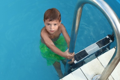 Little child getting out of outdoor swimming pool. Dangerous situation