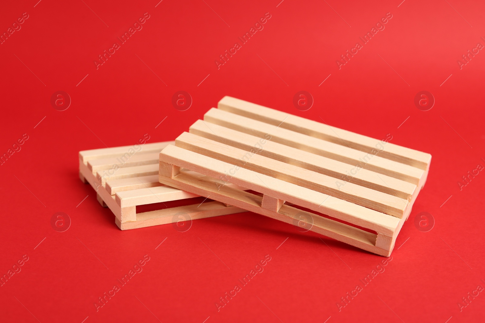 Photo of Two small wooden pallets on red background