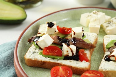 Delicious sandwiches with anchovies, cheese and tomato on white table, closeup