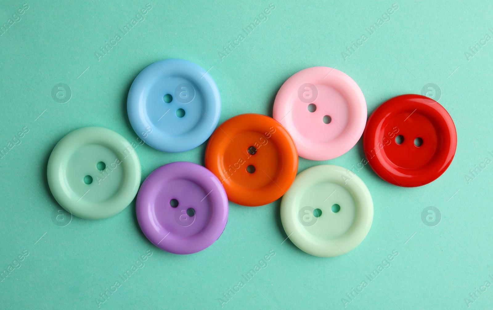 Photo of Many colorful sewing buttons on turquoise background, flat lay