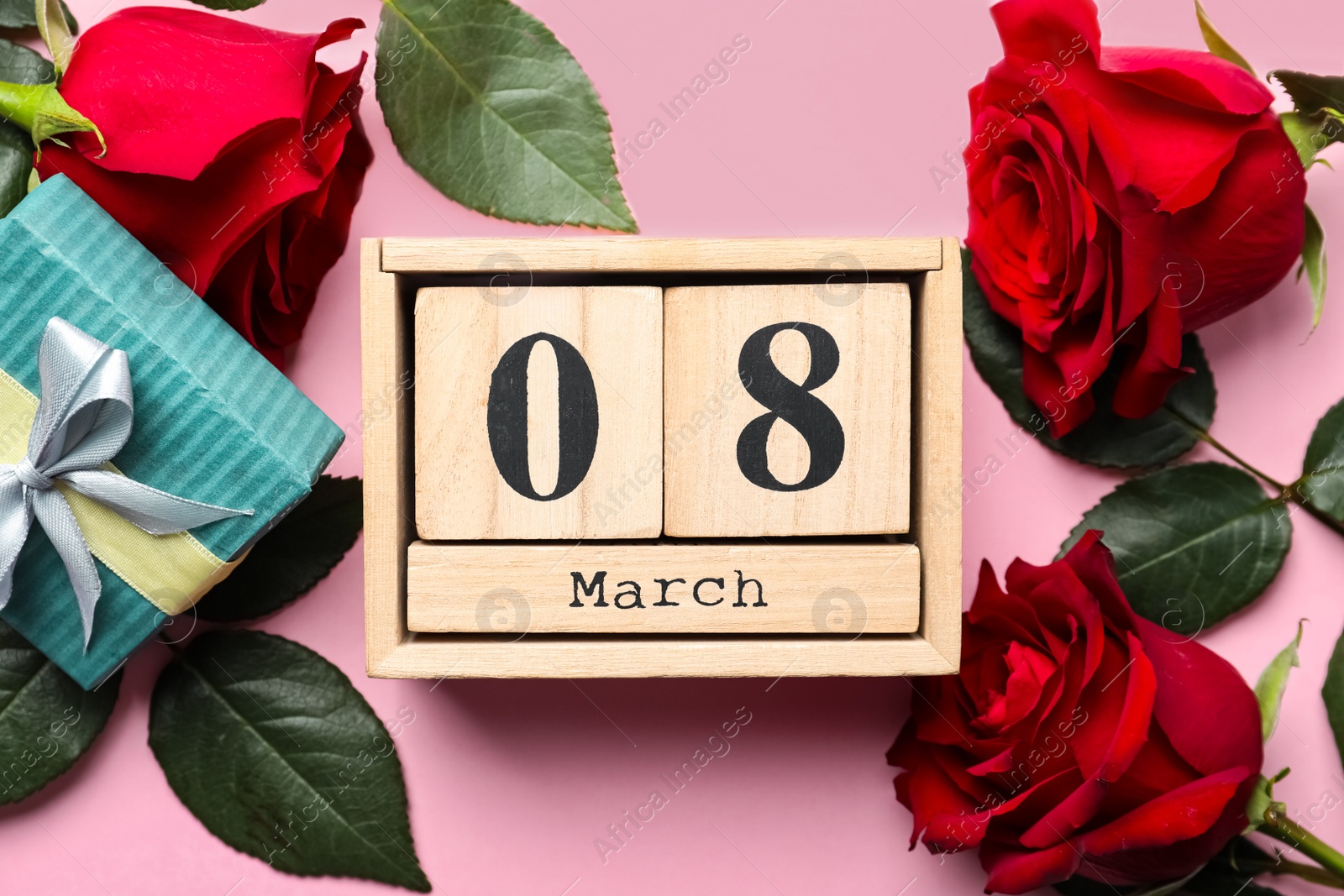 Photo of Wooden block calendar with date 8th of March, roses and gift box on pink background, flat lay. International Women's Day