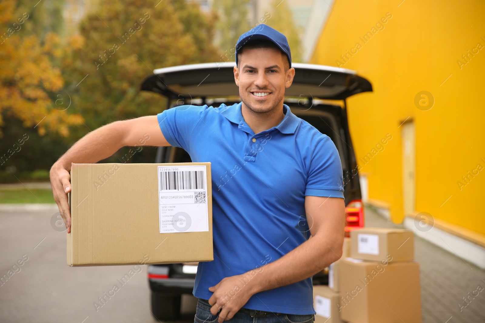 Photo of Courier with parcel near delivery van outdoors