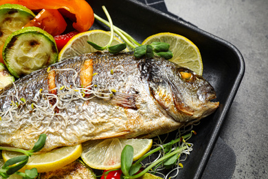 Photo of Delicious roasted fish and vegetables on grey table, closeup view