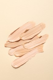 Photo of Samples of skin foundation on beige background, top view