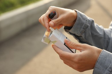 Woman taking cigarette out of pack outdoors, closeup