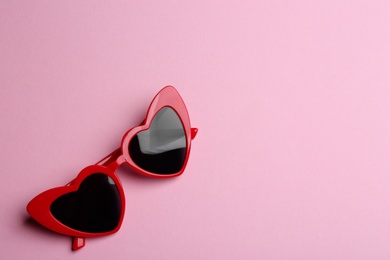 Stylish heart shaped sunglasses on pink background, top view with space for text. Fashionable accessory