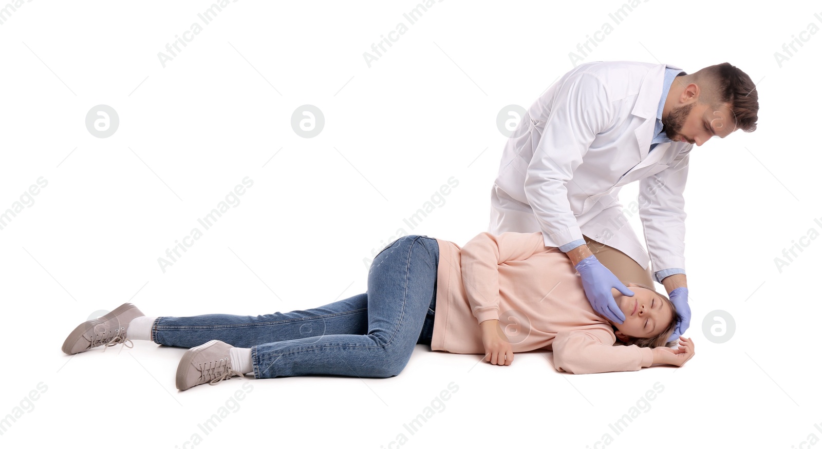 Photo of Doctor in uniform performing first aid on unconscious woman against white background