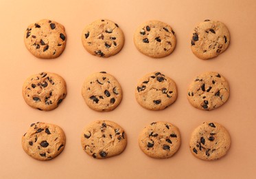 Photo of Many delicious chocolate chip cookies on beige background, flat lay