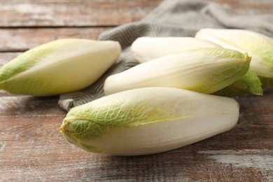 Photo of Fresh raw Belgian endives (chicory) on wooden table, closeup