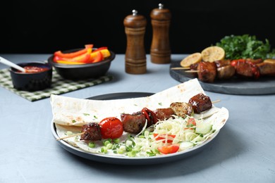 Photo of Delicious shish kebab with vegetables served on gray table, closeup