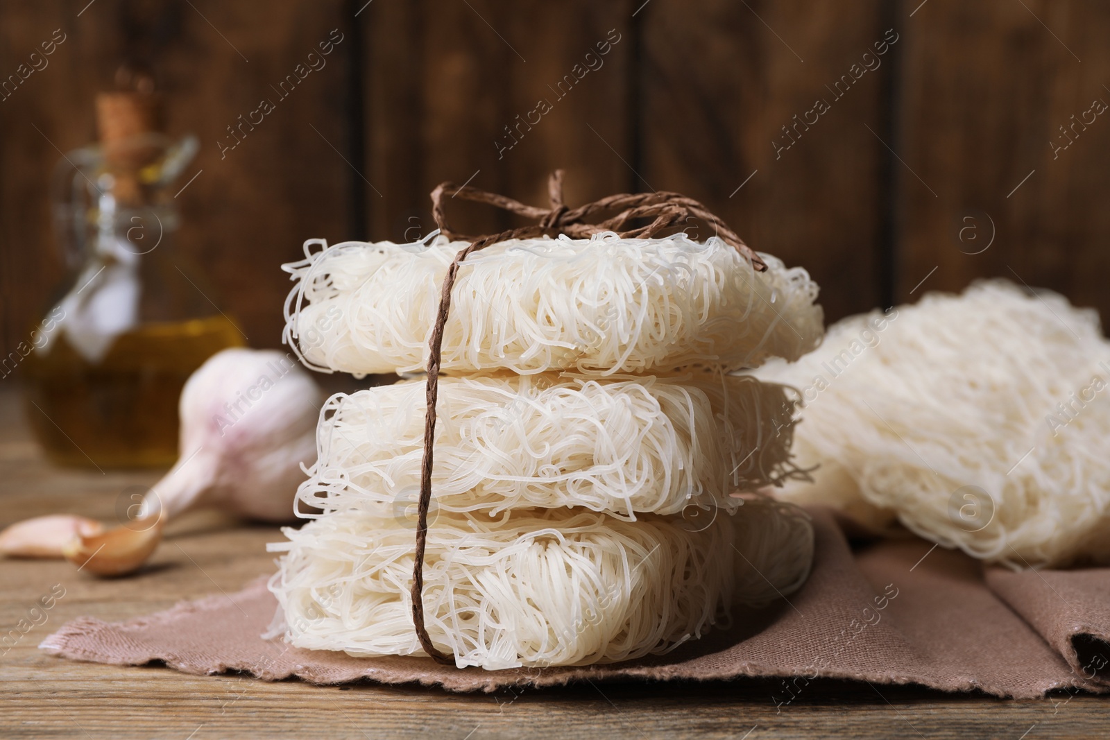 Photo of Stacked uncooked rice noodles on wooden table