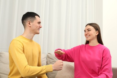 Happy people playing rock, paper and scissors in room