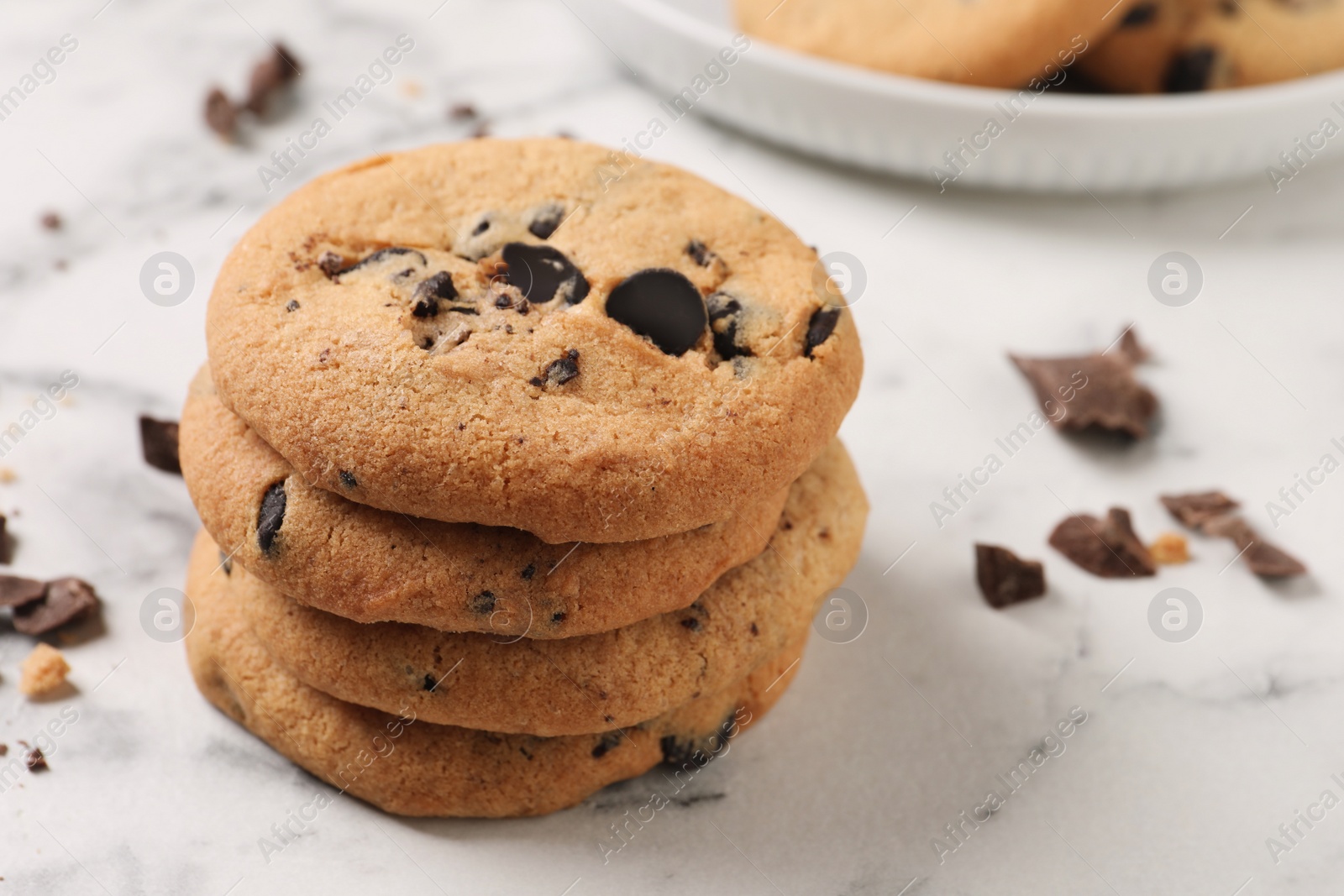 Photo of Delicious chocolate chip cookies on white marble table. Space for text