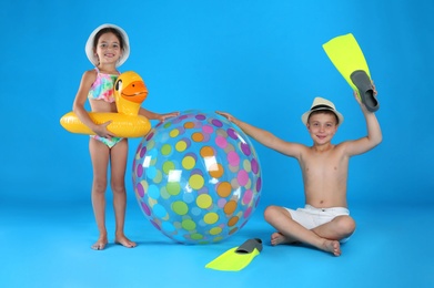 Photo of Cute little children in beachwear with inflatable toys on light blue background