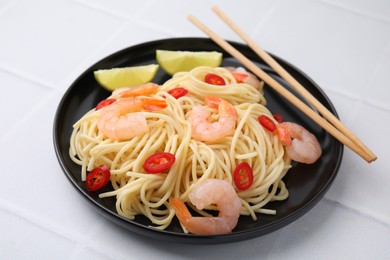 Photo of Tasty spaghetti with shrimps, chili pepper and lime on light tiled table, closeup