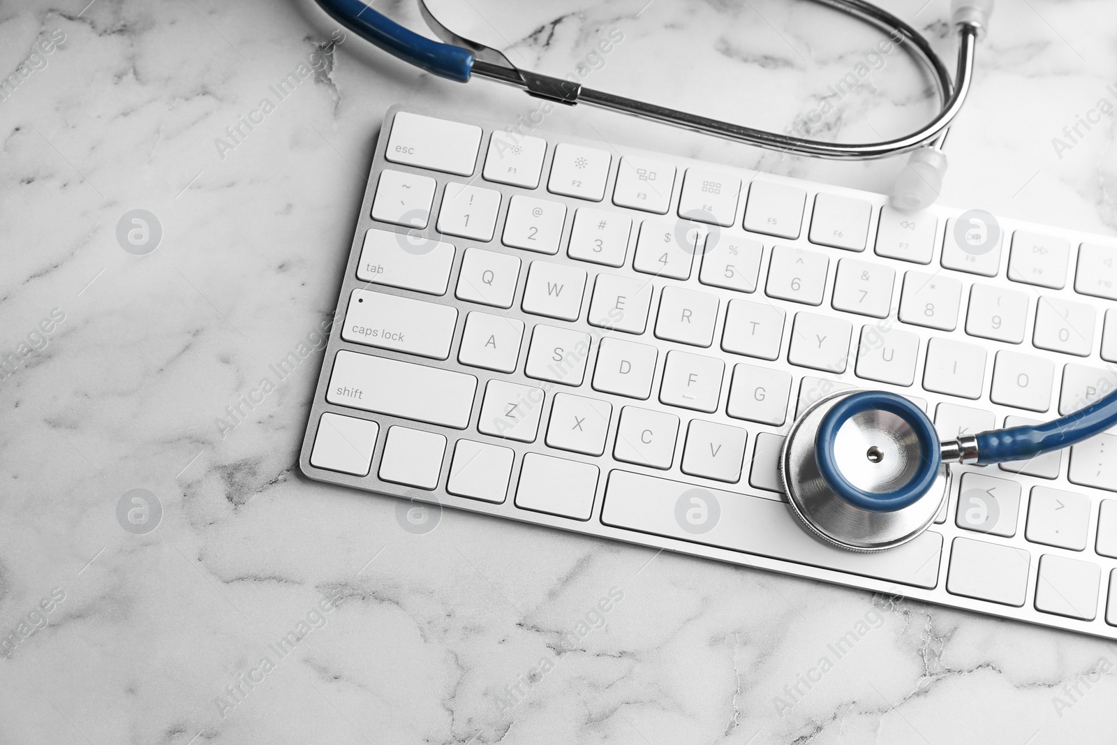 Photo of Keyboard and stethoscope on white marble table, flat lay. Concept of technical support