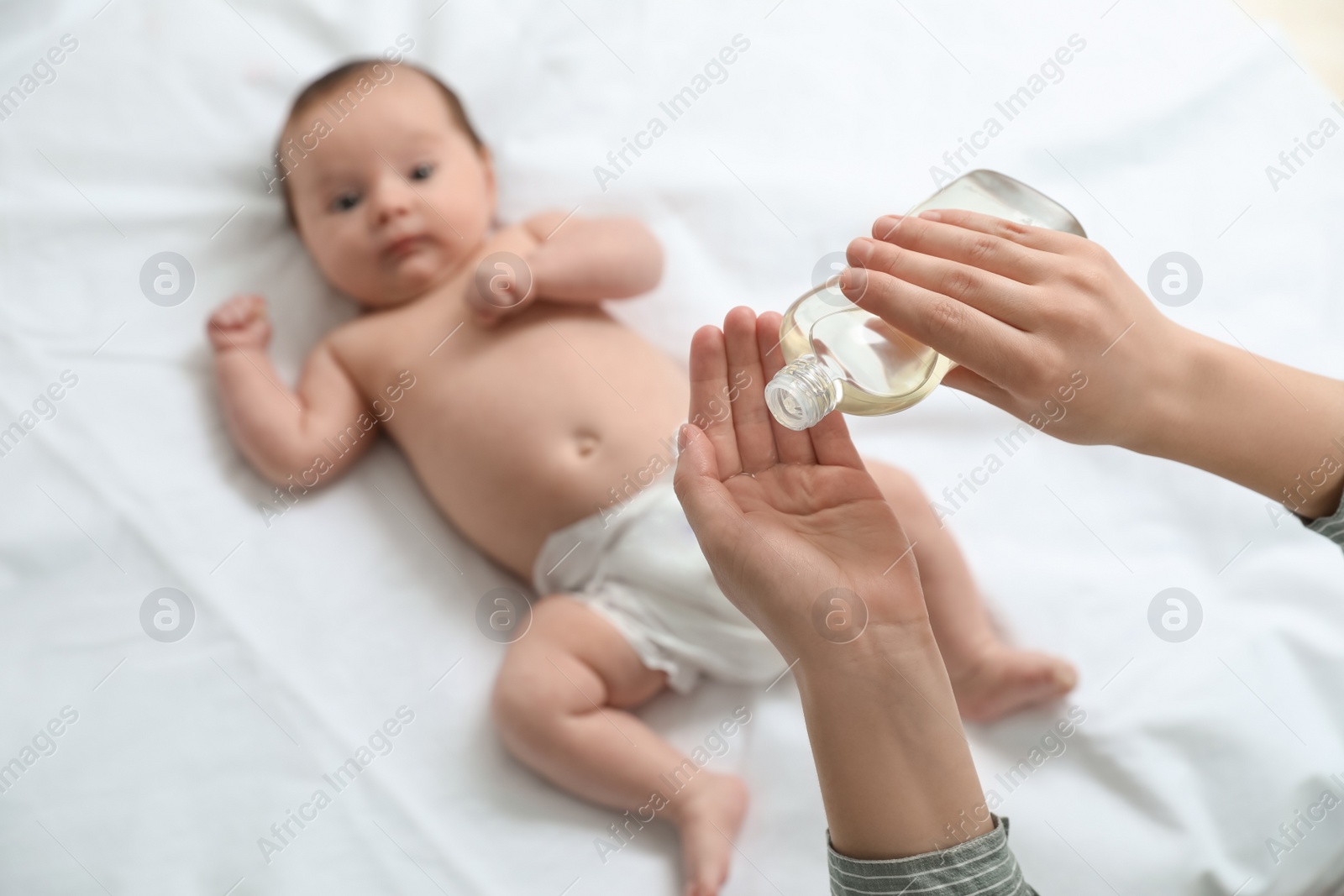 Photo of Mother with massaging oil near her cute baby, closeup