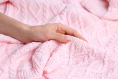 Photo of Woman touching soft light pink knitted sweater, closeup