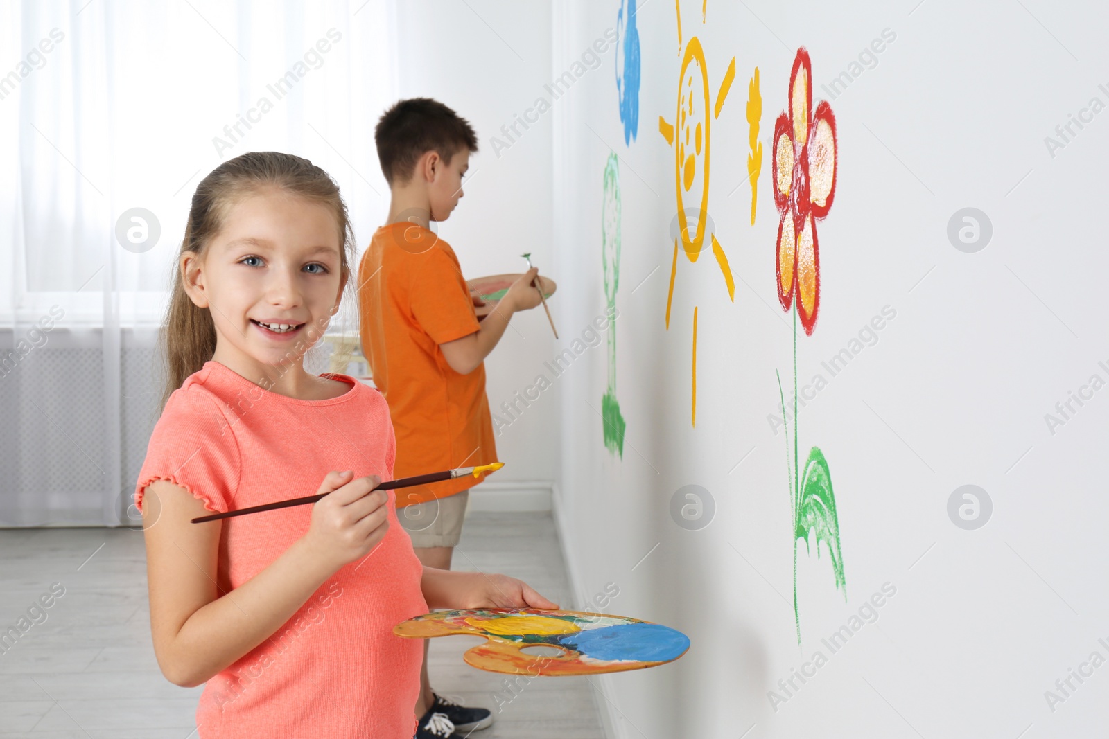 Photo of Little children painting on white wall indoors