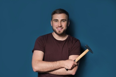 Photo of Young working man with hammer on color background
