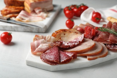 Photo of Cutting board with different sliced meat products served on table