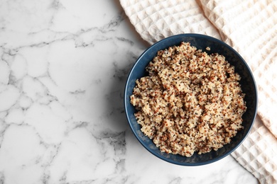 Cooked delicious quinoa in bowl on table, top view. Space for text