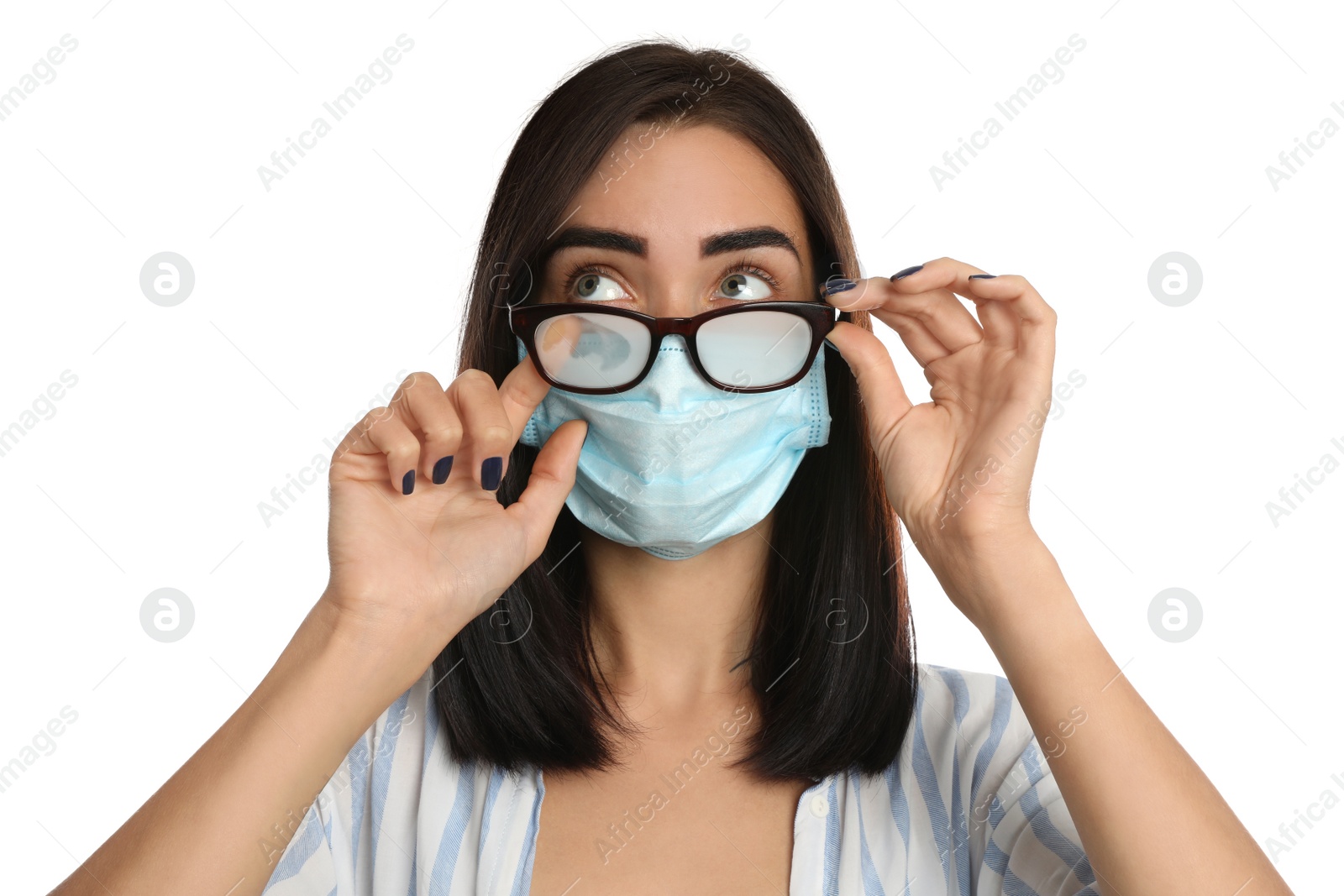 Photo of Young woman wiping foggy glasses caused by wearing disposable mask on white background. Protective measure during coronavirus pandemic