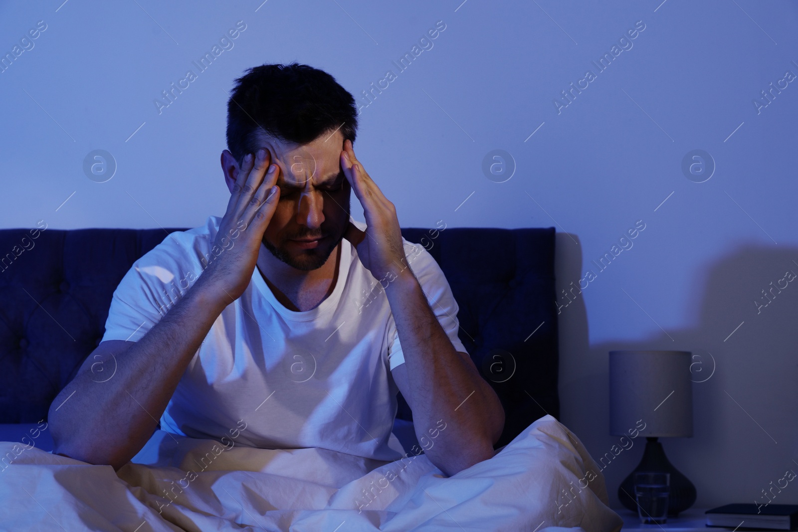 Photo of Sleepy handsome man sitting in dark room at night. Bedtime
