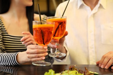 Photo of Lovely couple with Aperol spritz cocktails resting together at restaurant, closeup