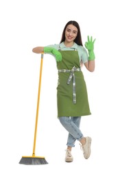 Beautiful young woman with broom showing OK gesture on white background