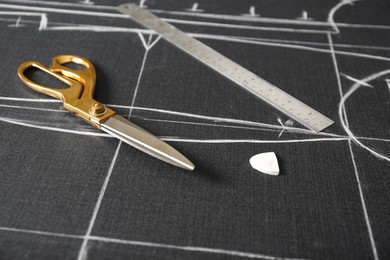 Photo of Scissors, tailor's chalk and ruler on grey fabric with sewing patterns