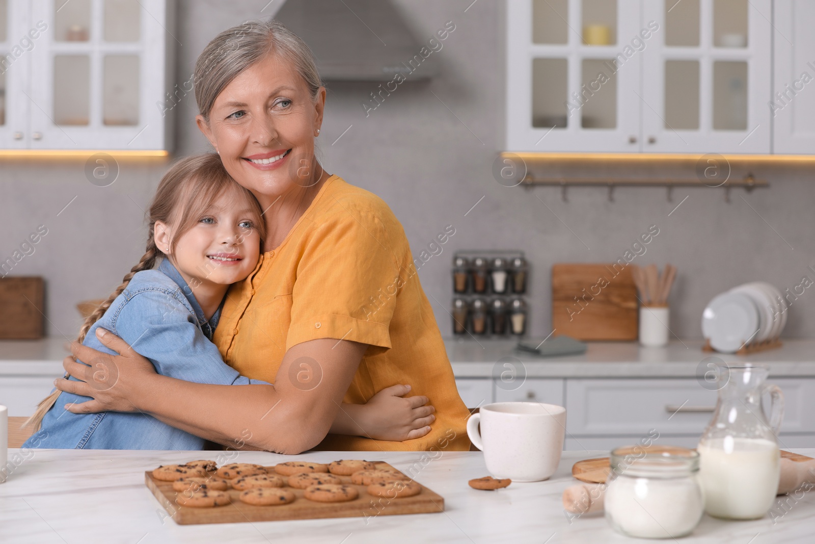 Photo of Happy grandmother hugging her granddaughter in kitchen