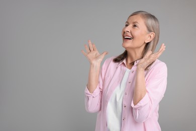 Photo of Portrait of surprised senior woman on grey background, space for text