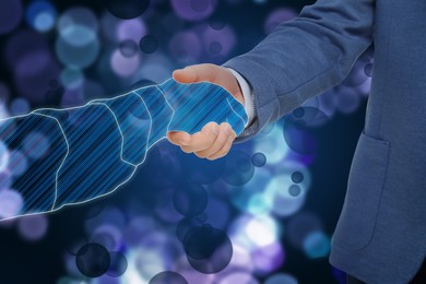Image of Businessman shaking hands with virtual partner on dark background, closeup. Illustration of digital hand