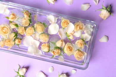 Heart shaped ice cubes with roses in glass dish on color background, top view