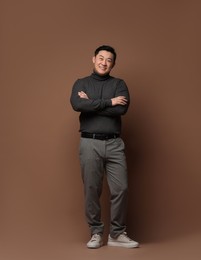 Full length portrait of happy man on brown background