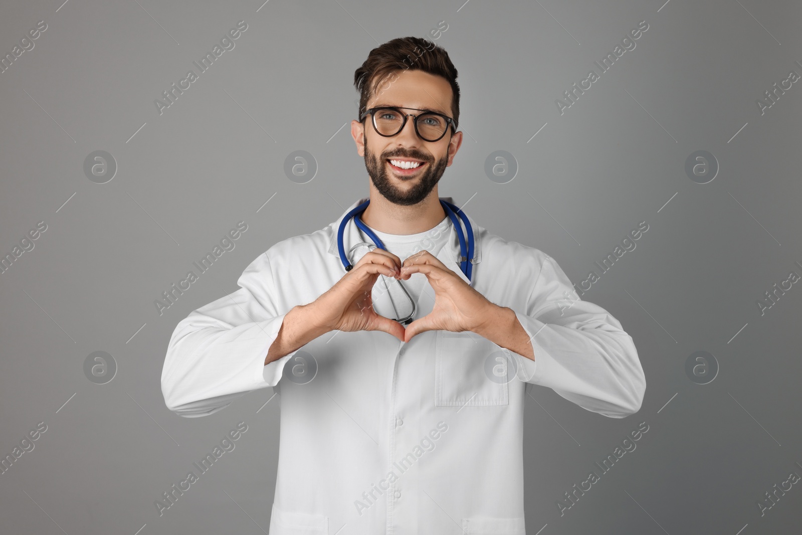 Photo of Doctor making heart with hands on grey background