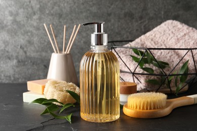 Photo of Stylish dispenser with liquid soap and other bathroom amenities on dark table