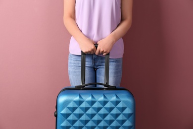 Photo of Young woman with suitcase on color background