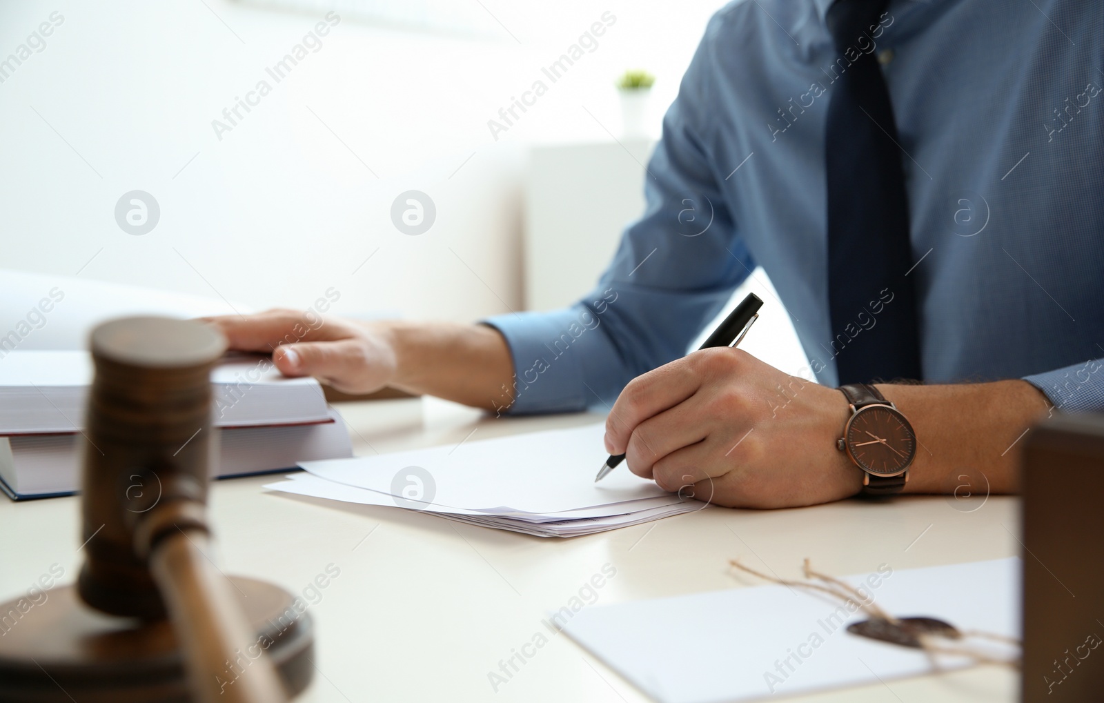 Photo of Notary working with papers and judge gavel on table, closeup. Law and justice concept