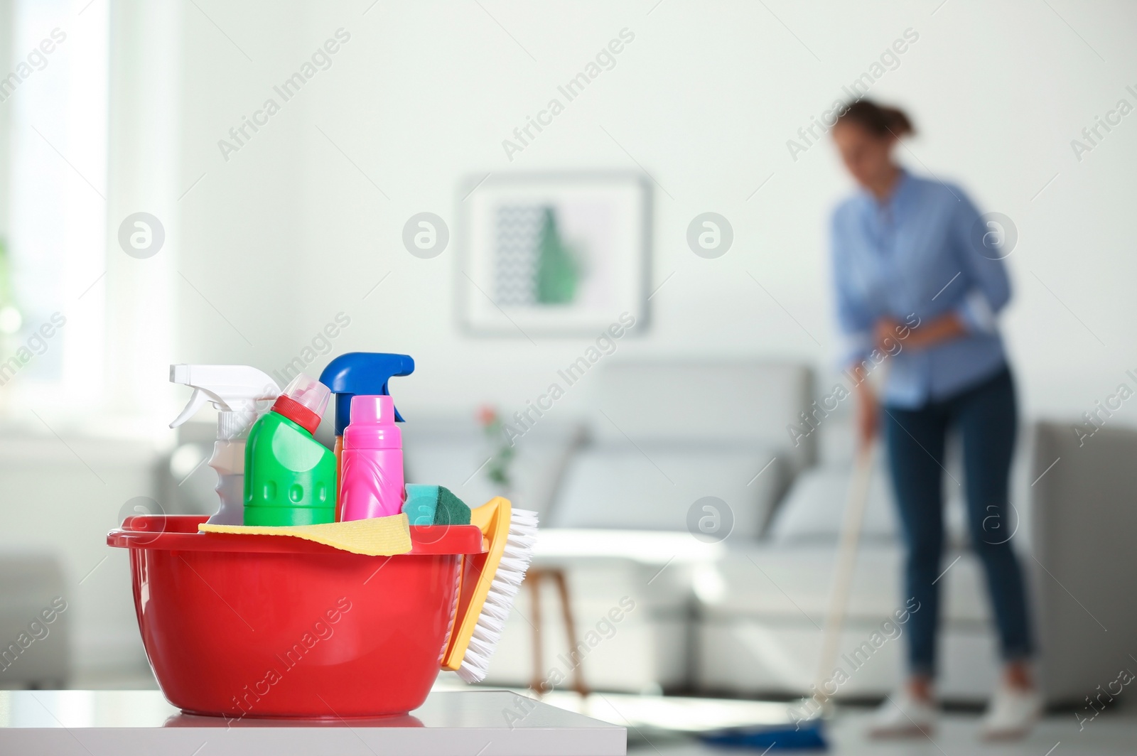 Photo of Basin with cleaning supplies and blurred woman on background