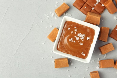 Photo of Gravy boat with salted caramel sauce and candies on table, top view