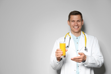 Photo of Nutritionist with glass of juice on light grey background. Space for text