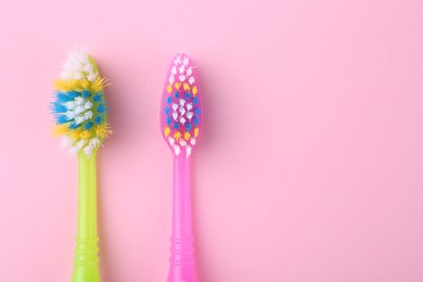 Colorful plastic toothbrushes on pink background, flat lay. Space for text