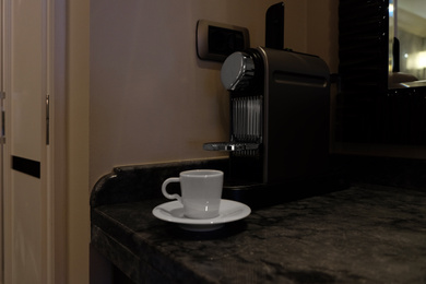 Photo of White cup near coffee machine on table