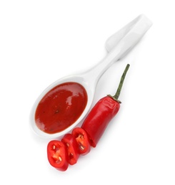 Photo of Spoon with spicy chili sauce and fresh pepper on white background, top view