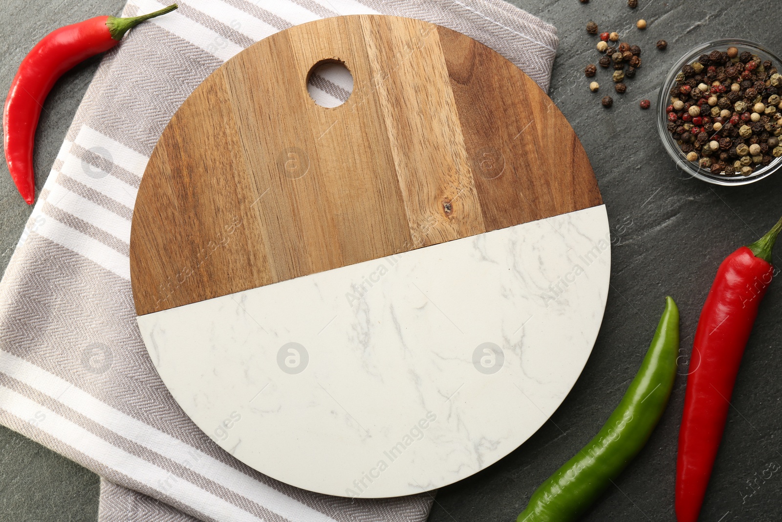 Photo of Cutting board, spices and kitchen towel on dark grey table, flat lay