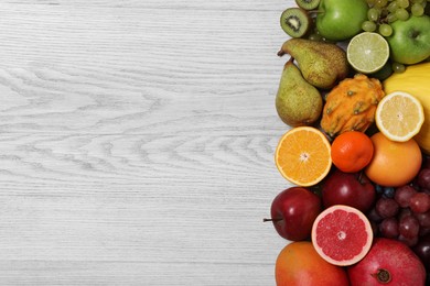 Many different fresh fruits on light wooden table, flat lay. Space for text