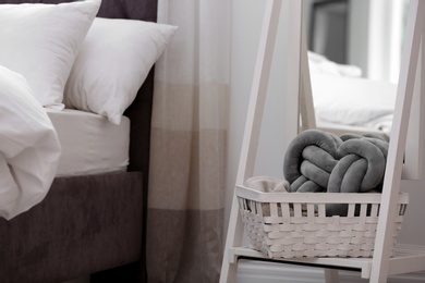 Photo of Basket with pillow near bed in room